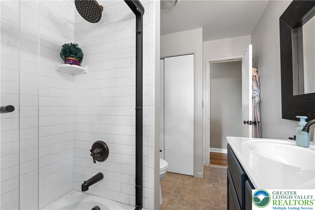 2569 Woods Edge Road Bath, PA 18014 - Photo 19 of 40 Crisp subway tile lines the shower enclosure adjacent to a modern vanity with dark cabinetry.