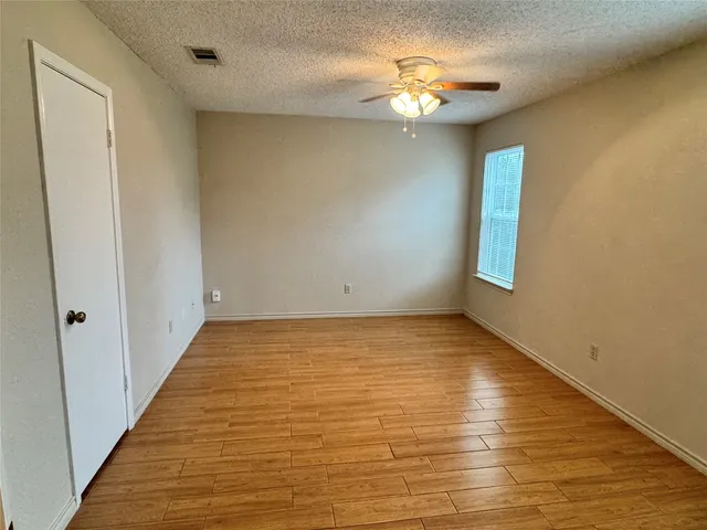 a view of an empty room with window and chandelier fan