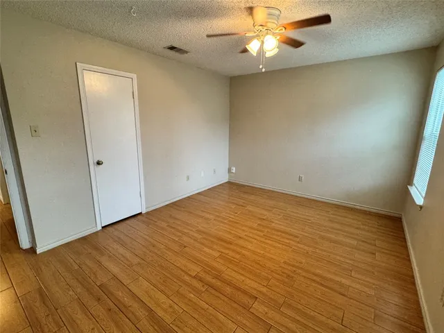 an empty room with wooden floor and fan