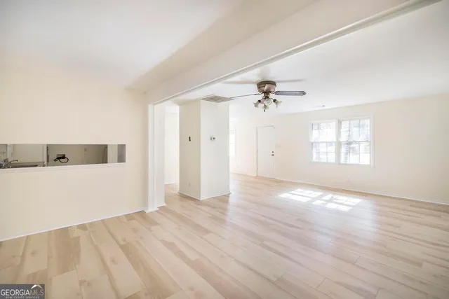 an empty room with wooden floor window and ceiling fan