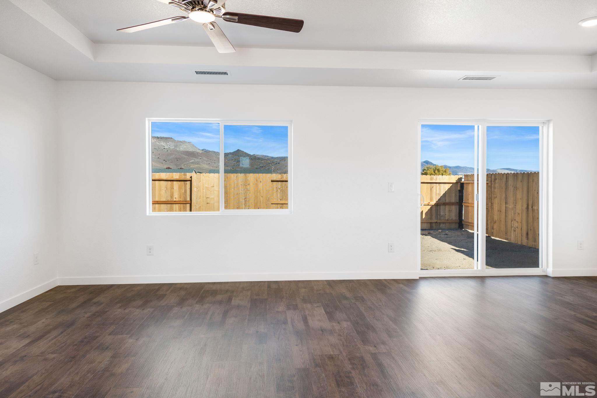 211 Green Lane Dayton, NV 89403 - Photo 9 of 28 an empty room with wooden floor chandelier fan and windows