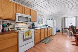 a kitchen with stainless steel appliances granite countertop a stove top oven a sink dishwasher and white cabinets with wooden floor