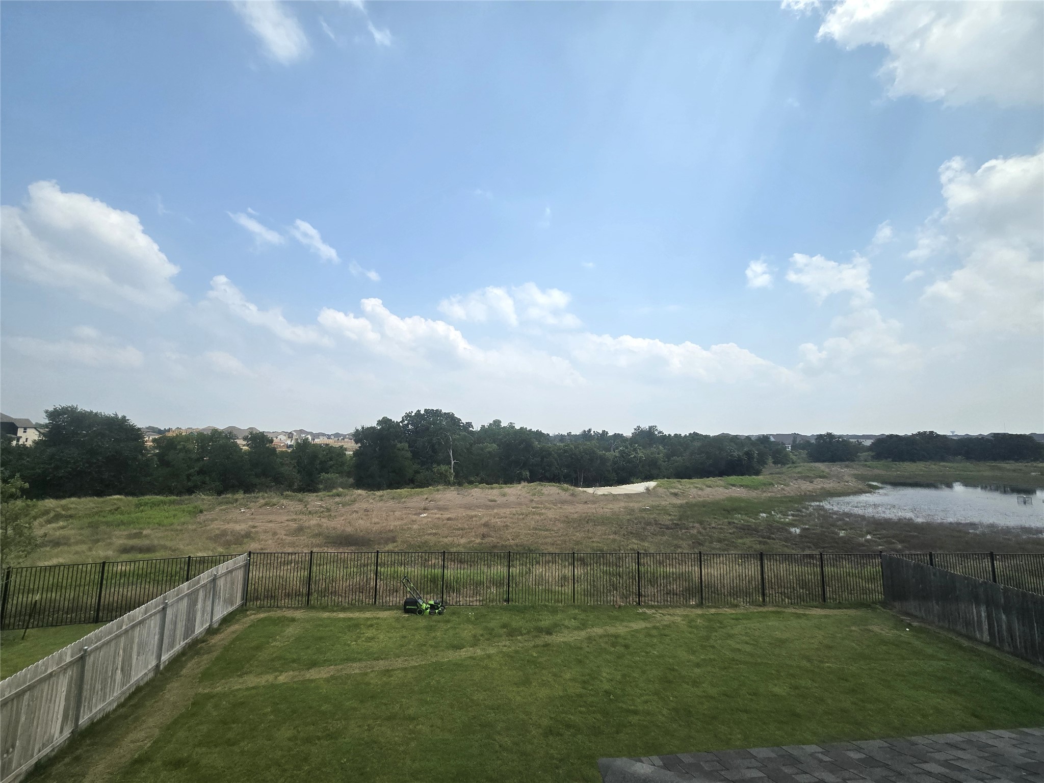 124 Ribera Drive Liberty Hill, TX 78642 - Photo 28 of 40 A verdant lawn meets an expansive natural landscape with a tranquil pond, offering peaceful outdoor living.
