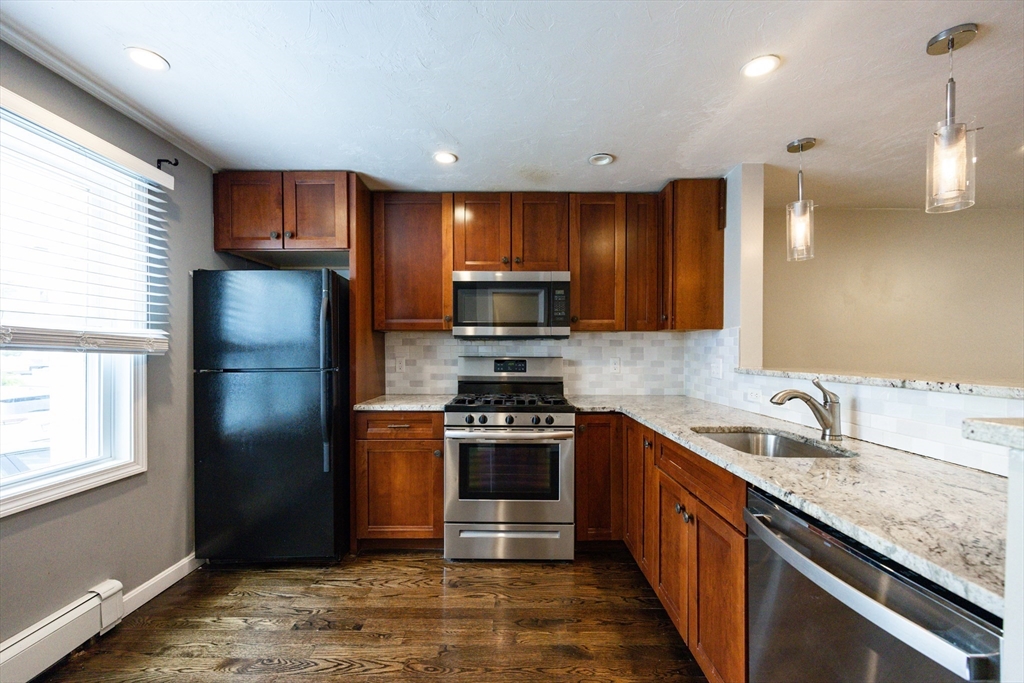 210 West Sixth Street, Unit 210 Boston, MA 02127 - Photo 5 of 36 a kitchen with granite countertop stainless steel appliances and wooden cabinets