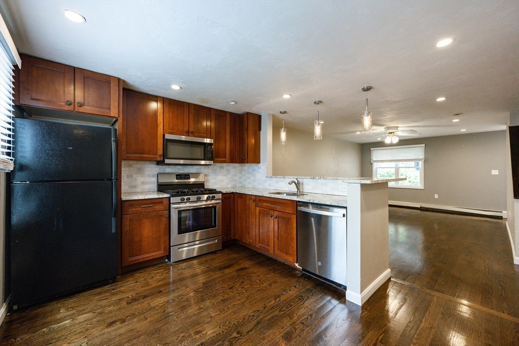 210 West Sixth Street, Unit 210 Boston, MA 02127 - Photo 7 of 36 a kitchen with stainless steel appliances kitchen island granite countertop a stove a sink and a refrigerator