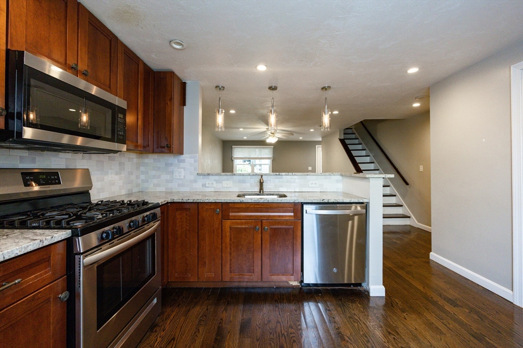 210 West Sixth Street, Unit 210 Boston, MA 02127 - Photo 8 of 36 a kitchen with stainless steel appliances kitchen island granite countertop a stove a sink and a microwave