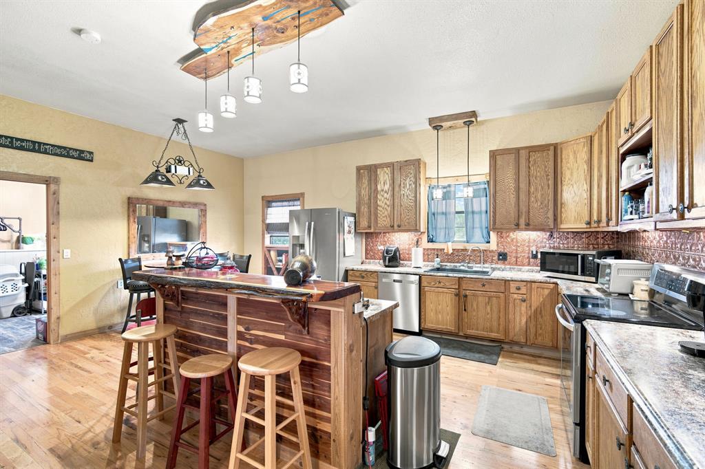 5821 Waterworks Road Midlothian, TX 76065 - Photo 6 of 36 Kitchen features a custom built bar with cedar counter top and front. Notice the custom made light fixture also. All trim thoughout is cedar.