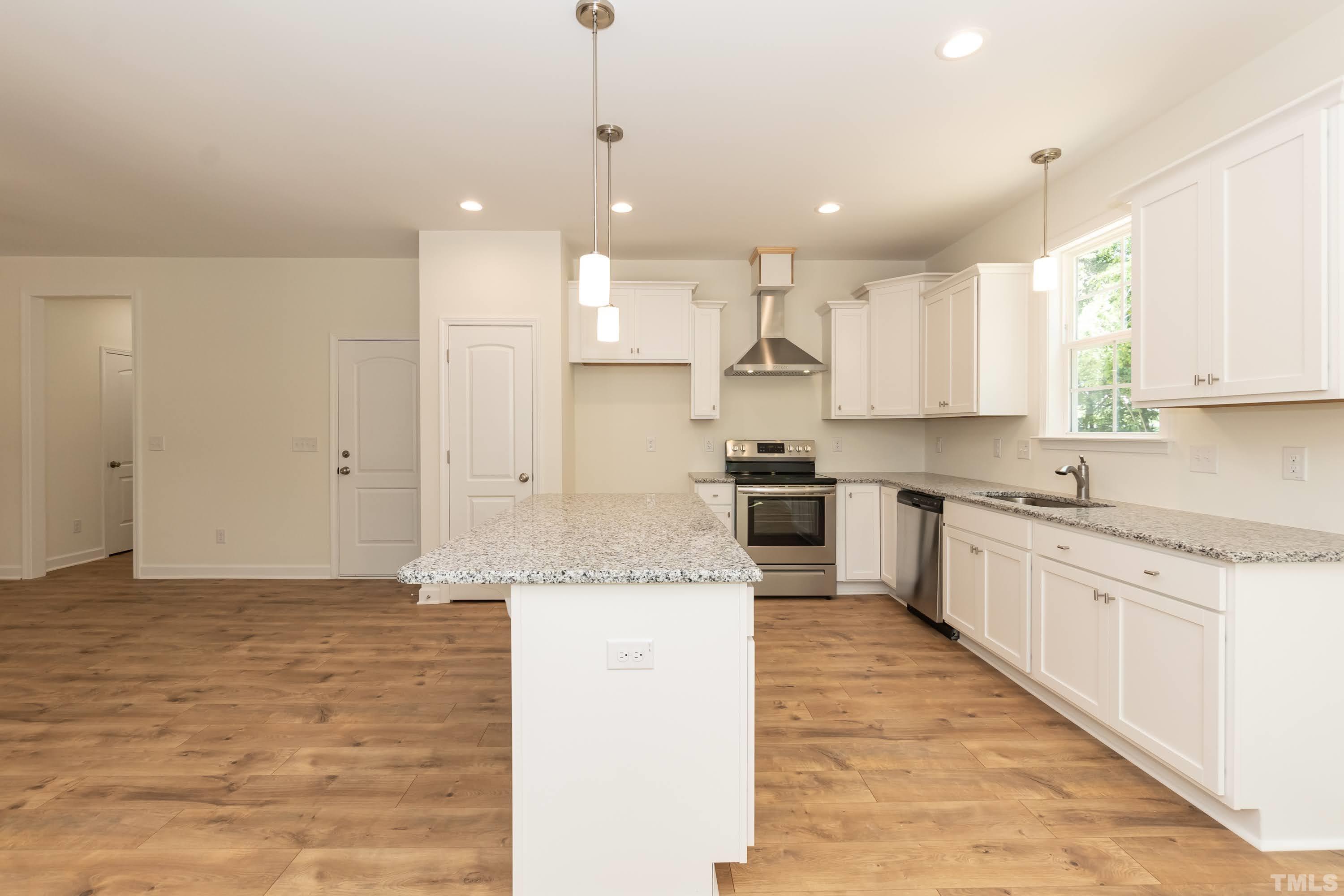 119 Carriage Loop Burlington, NC 27217 - Photo 10 of 29 a large kitchen with stainless steel appliances kitchen island granite countertop a stove a sink a refrigerator and white cabinets with wooden floor