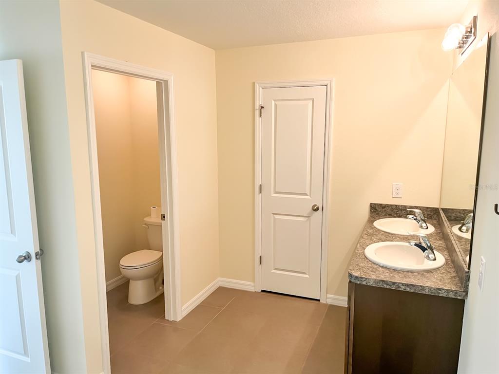 7690 Tuscan Bay Circle Wesley Chapel, FL 33545 - Photo 12 of 14 a bathroom with a granite countertop sink a toilet and a mirror