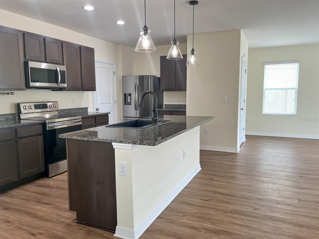 7690 Tuscan Bay Circle Wesley Chapel, FL 33545 - Photo 2 of 14 a kitchen with stainless steel appliances granite countertop a sink a stove a refrigerator and a microwave