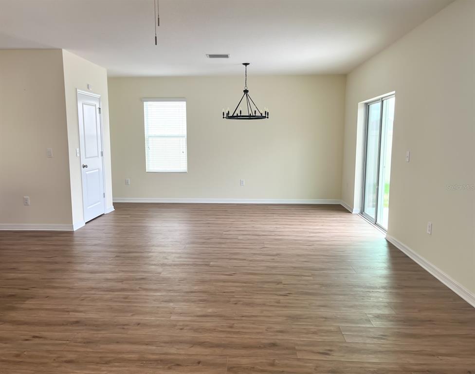 7690 Tuscan Bay Circle Wesley Chapel, FL 33545 - Photo 3 of 14 an empty room with wooden floor and windows