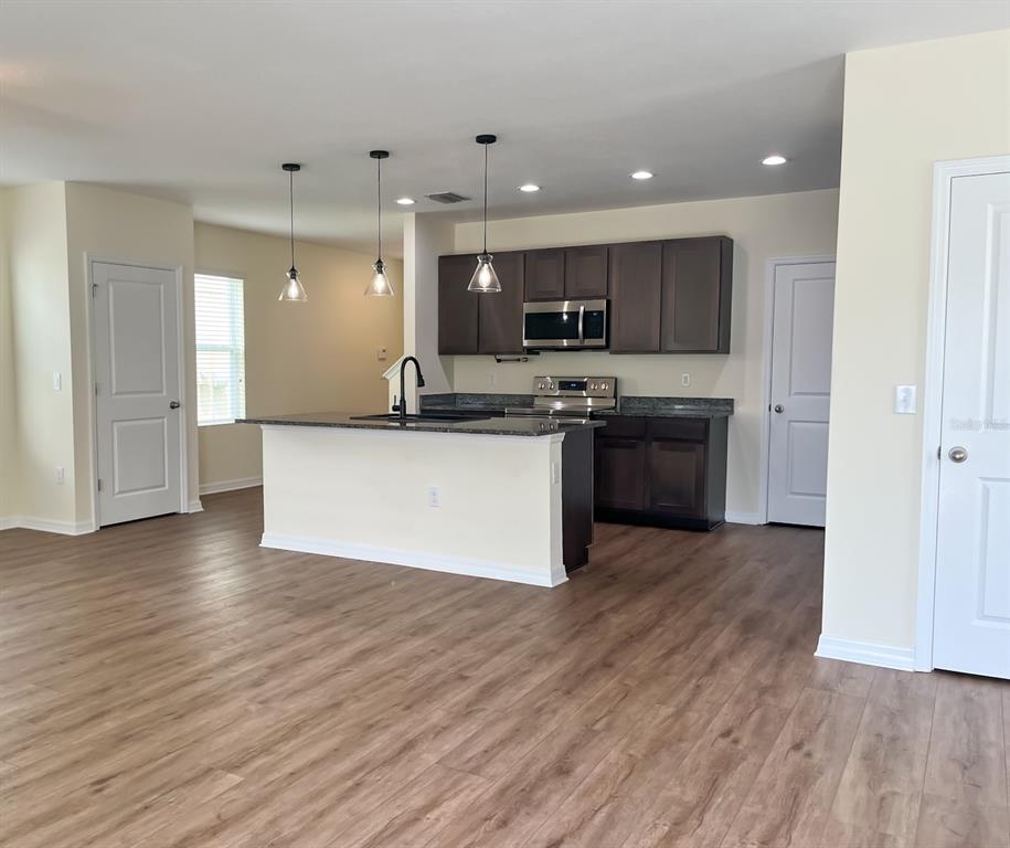 7690 Tuscan Bay Circle Wesley Chapel, FL 33545 - Photo 4 of 14 a large kitchen with stainless steel appliances granite countertop a stove top oven a sink and a microwave
