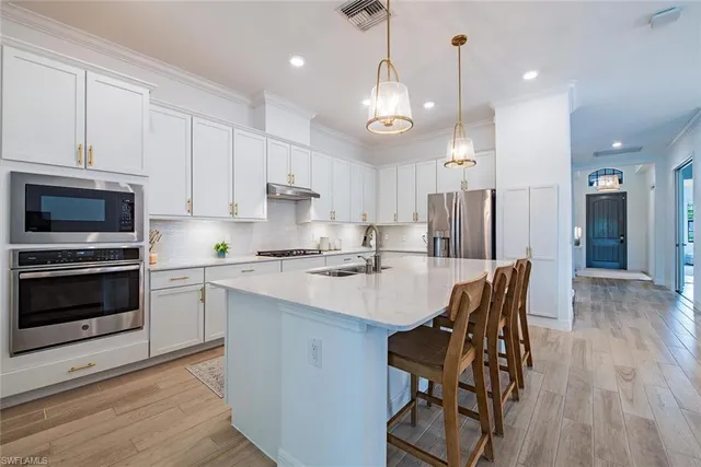 a kitchen with stainless steel appliances kitchen island granite countertop a stove a sink a refrigerator and a microwave