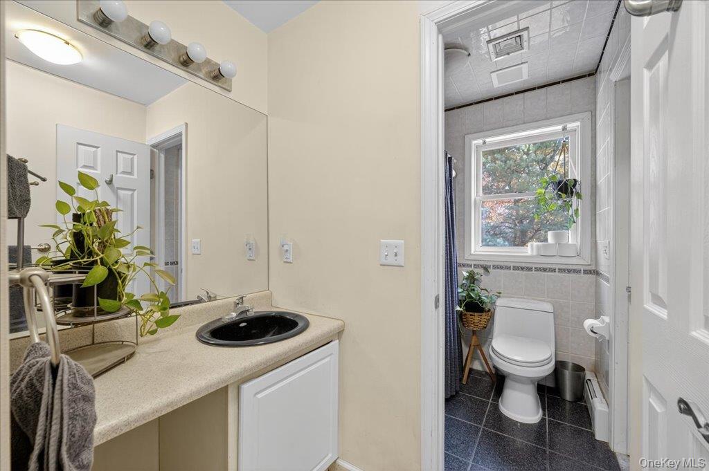 74 Pocatello Road Middletown, NY 10940 - Photo 14 of 21 Full bathroom featuring vanity, a shower with shower curtain, tile walls, and baseboard heating