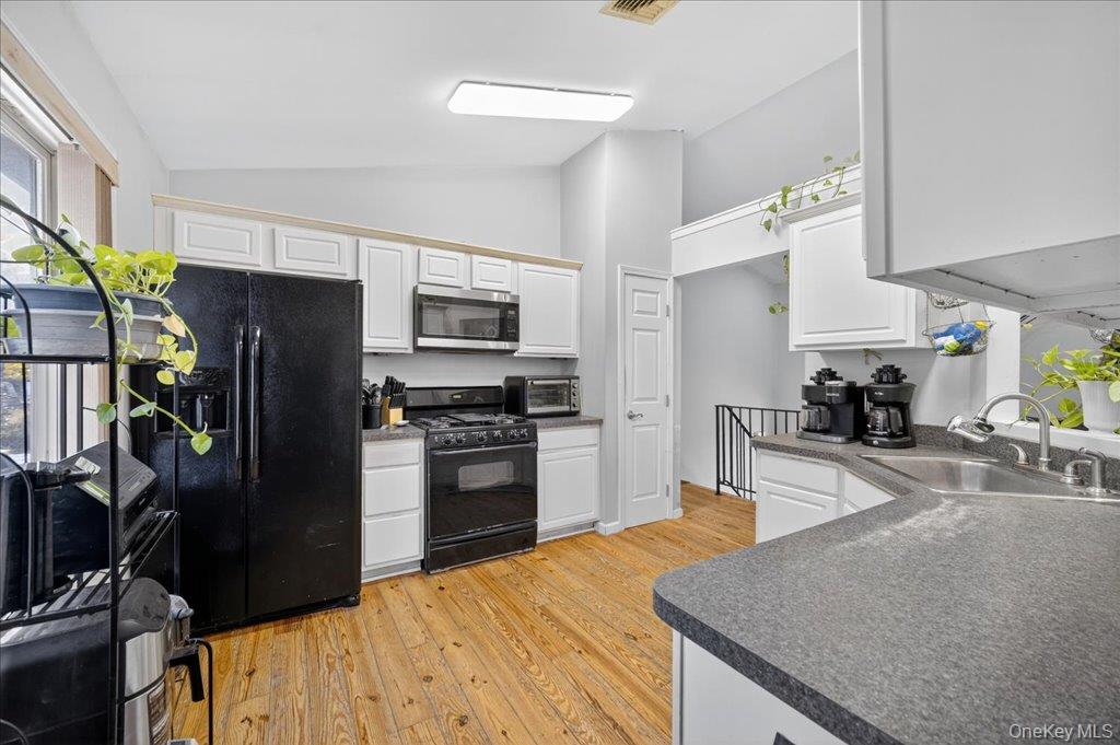 74 Pocatello Road Middletown, NY 10940 - Photo 10 of 21 Kitchen with light wood-type flooring, black appliances, lofted ceiling, and white cabinets