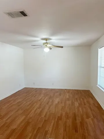 a view of an empty room with chandelier fan and a window