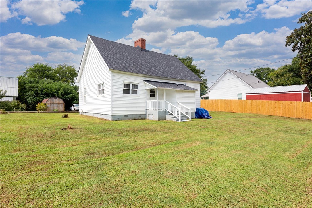7 McCaughrin Street Pelzer, SC 29669 - Photo 24 of 24 A well-maintained lawn extends around this charming white home with a classic gabled roof and a cozy back porch.