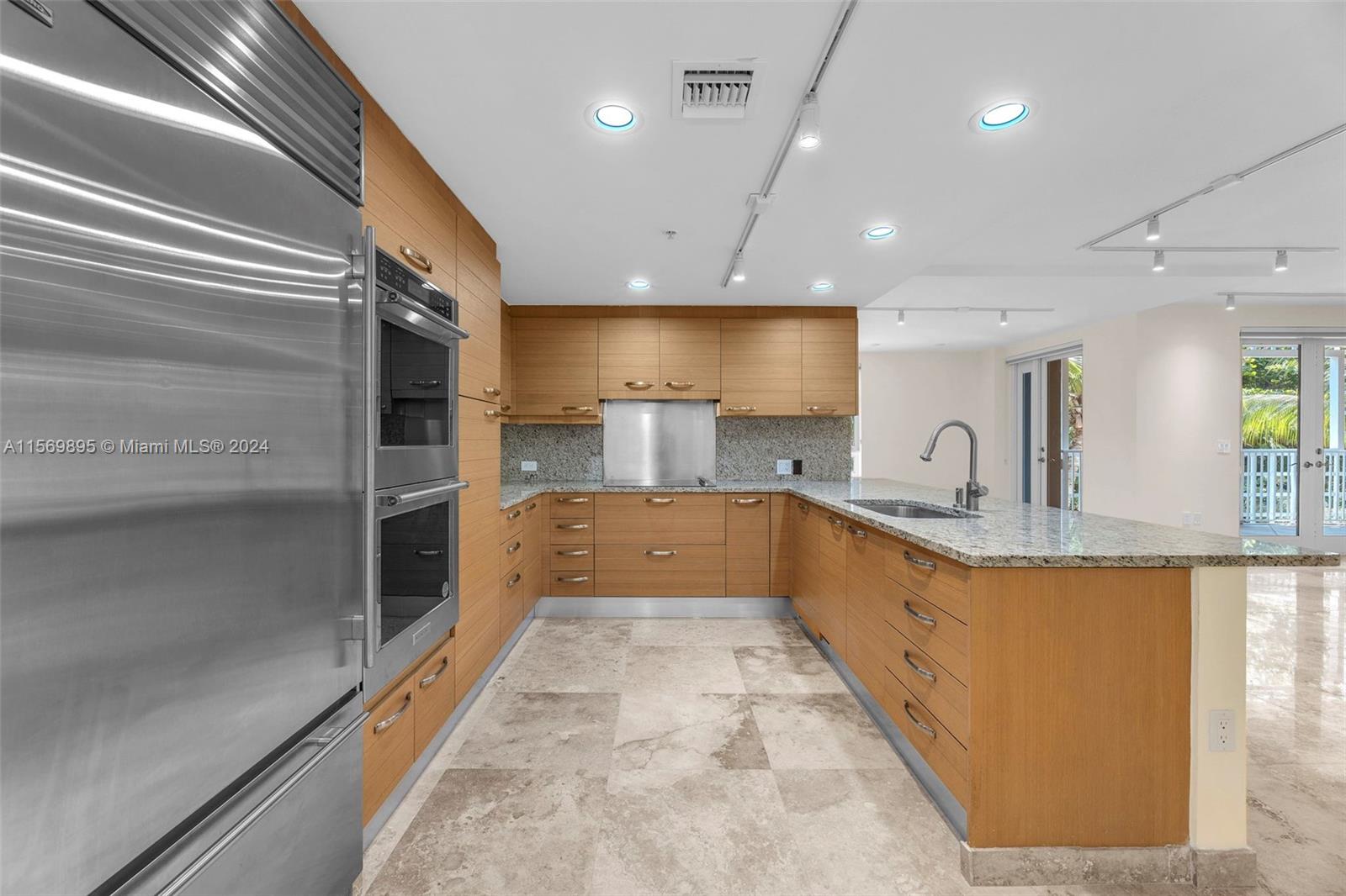 3540 Main Highway, Unit 310 Miami, FL 33133 - Photo 5 of 47 a large kitchen with stainless steel appliances kitchen island a large counter top a sink and a refrigerator