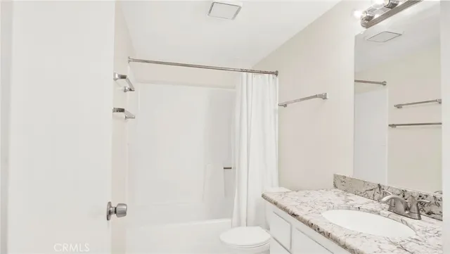 a bathroom with a granite countertop shower mirror and a toilet