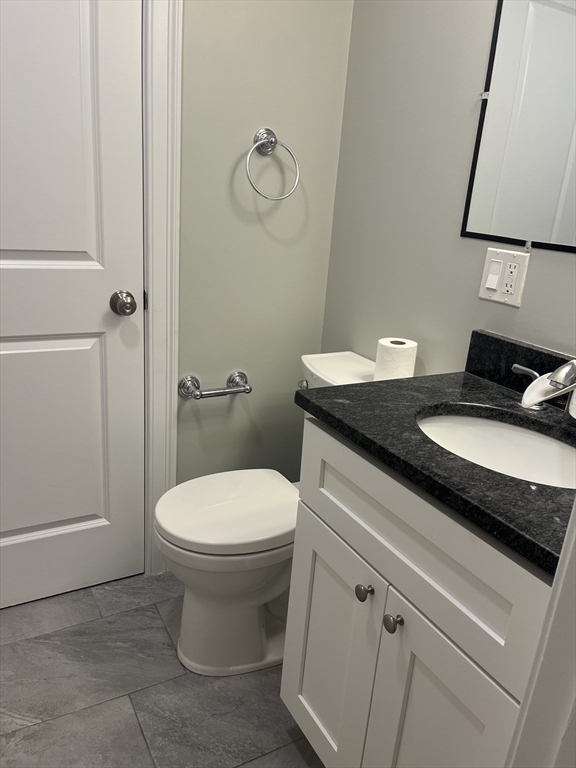 45 Spring Street, Unit 18 Boston, MA 02132 - Photo 6 of 29 a bathroom with a granite countertop toilet sink and mirror