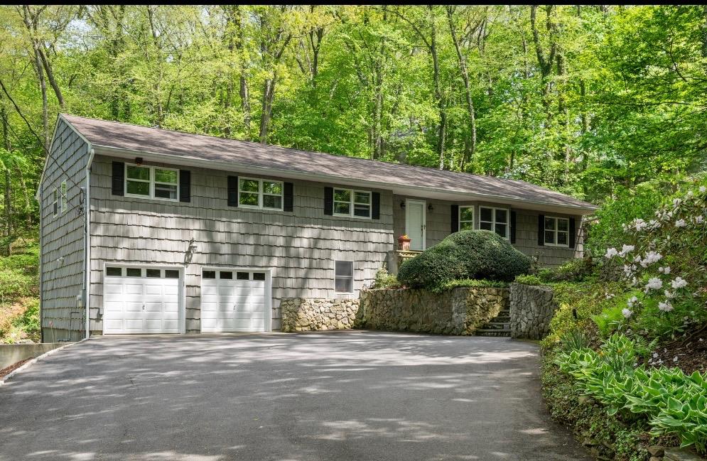 96 Bay Road Huntington, NY 11743 - Photo 1 of 1 View of front of house with asphalt driveway, an attached garage, a shingled roof, and a wooded view