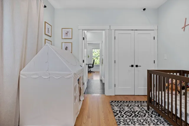 a view of a hallway with wooden floor and a bathroom