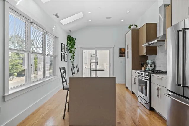 a kitchen with stainless steel appliances granite countertop a refrigerator a stove top oven a sink dishwasher and white cabinets next to a window