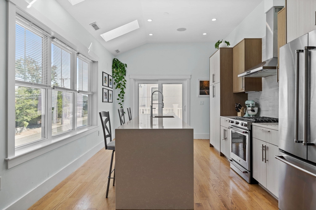 11 Ashland Street, Unit 2 Boston, MA 02122 - Photo 2 of 34 a kitchen with stainless steel appliances granite countertop a refrigerator a stove top oven a sink dishwasher and white cabinets next to a window