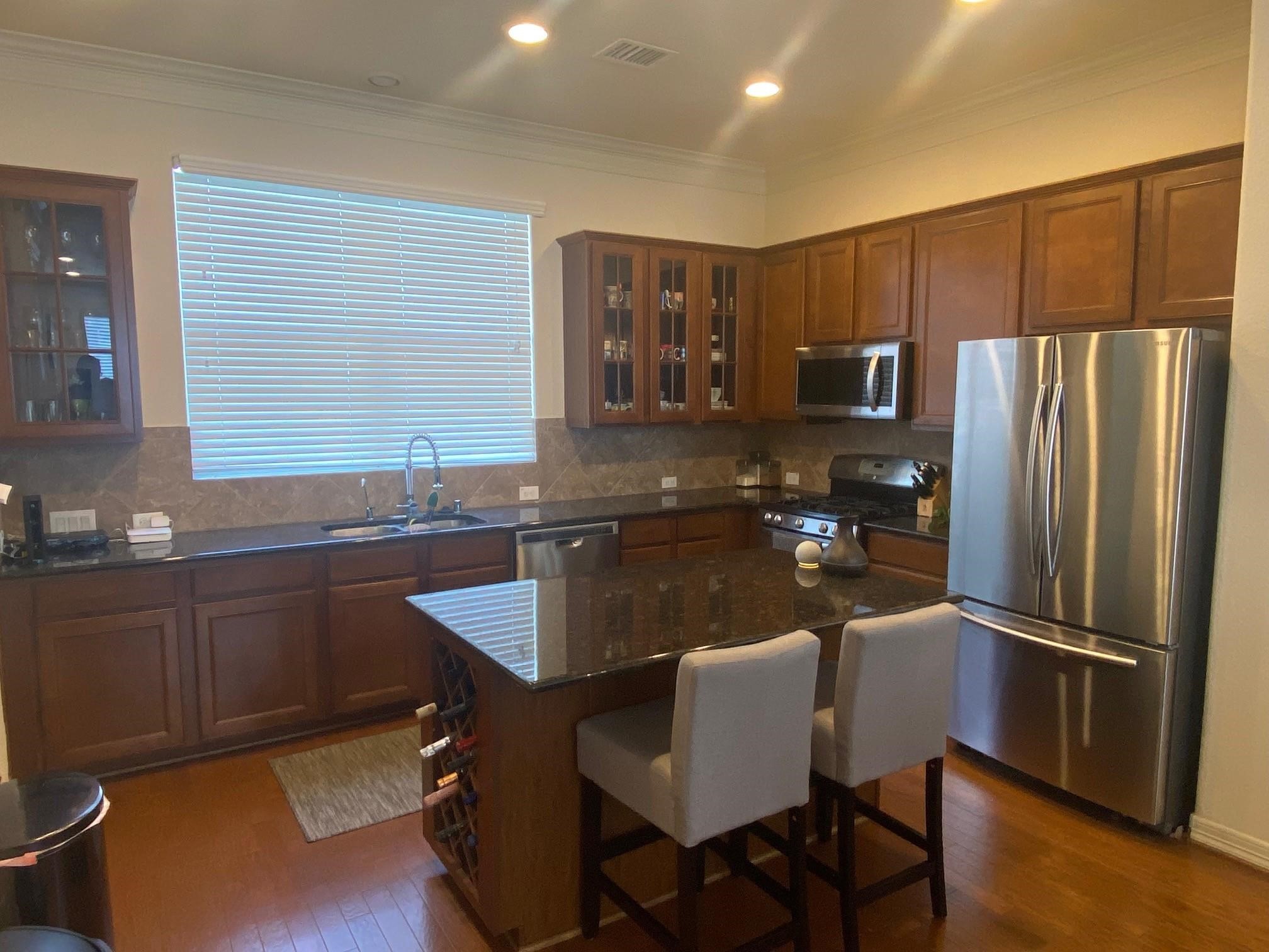 3209 Clearview Circle Houston, TX 77025 - Photo 6 of 13 a kitchen with stainless steel appliances granite countertop a refrigerator a sink dishwasher a stove a dining table and chairs with wooden floor
