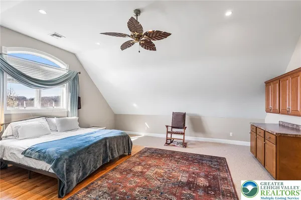 a bedroom with a bed a dresser and potted plant with the wooden floor