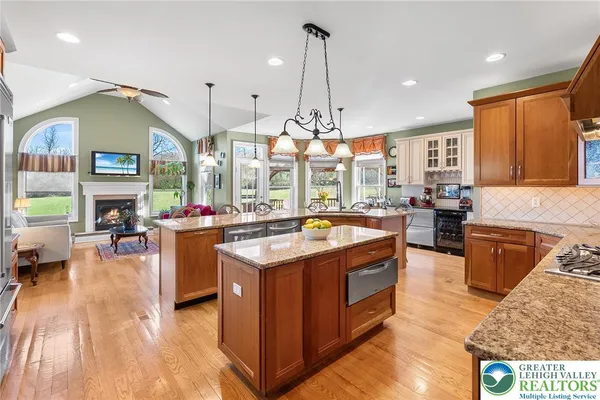 a kitchen with stainless steel appliances granite countertop a stove a sink dishwasher and a flat screen tv