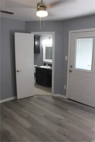a view of an empty room with wooden floor and closet