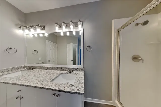 a bathroom with a granite countertop sink a mirror and a shower