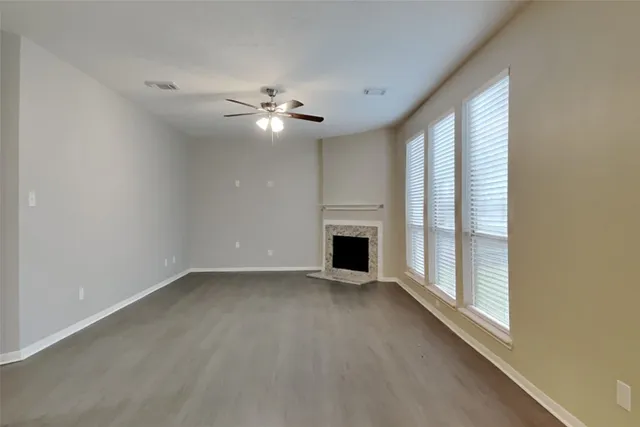an empty room with windows fireplace and fans