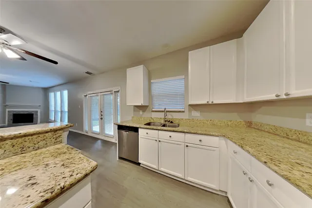 a large kitchen with granite countertop a sink and white cabinets