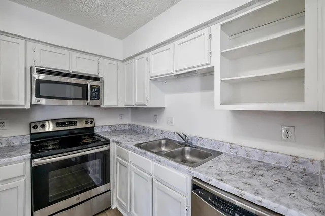 a kitchen with cabinets appliances a sink and a counter top
