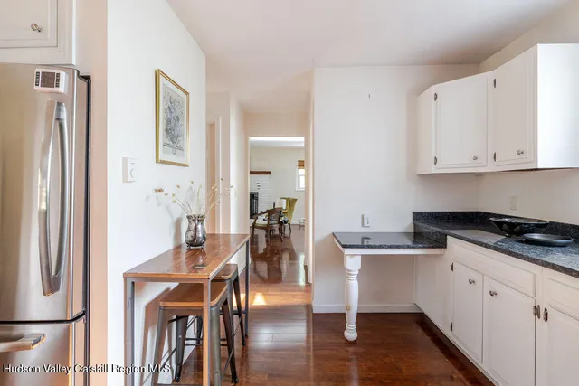 a kitchen with stainless steel appliances granite countertop a refrigerator a stove a white table and chairs