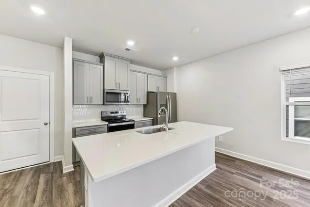 a kitchen with a sink a stove a refrigerator and white cabinets