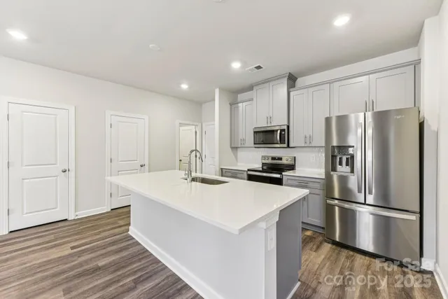 a kitchen with stainless steel appliances a refrigerator sink and microwave