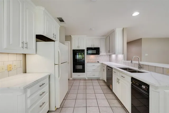 a kitchen with a sink white cabinets and stainless steel appliances