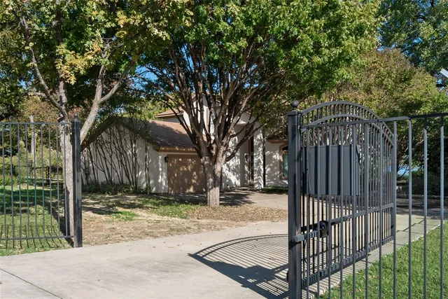 a view of a backyard with large trees and wooden fence