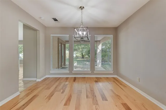an empty room with wooden floor mirror and windows