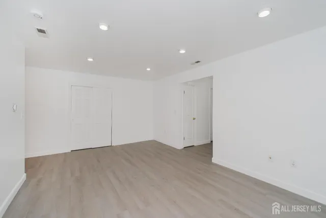a view of an empty room with wooden floor and closet