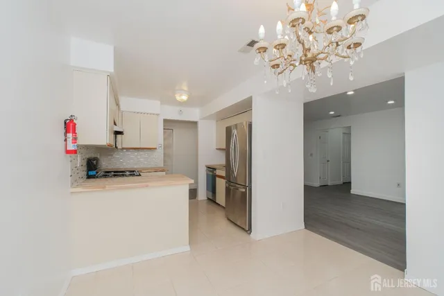 a kitchen that has a lot of white cabinets and stainless steel appliances