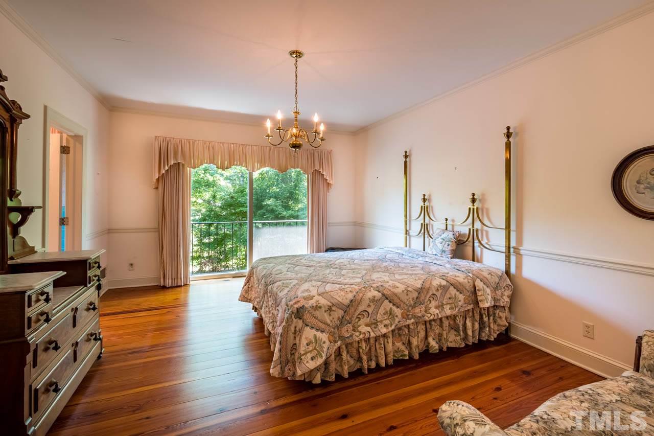 3210 Sussex Road Raleigh, NC 27612 - Photo 18 of 29 a bedroom with a bed and a chandelier