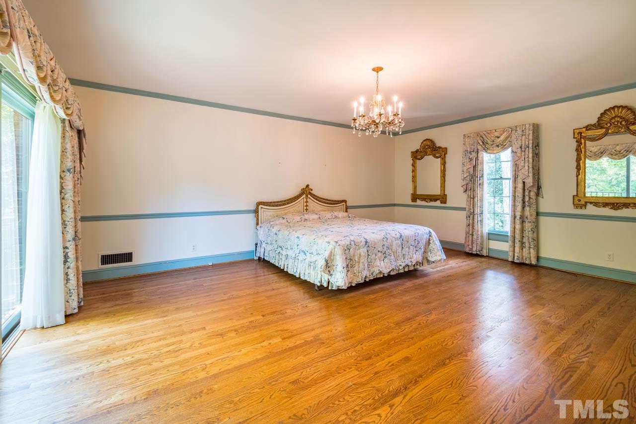 3210 Sussex Road Raleigh, NC 27612 - Photo 22 of 29 a bedroom with a bed chandelier and a window