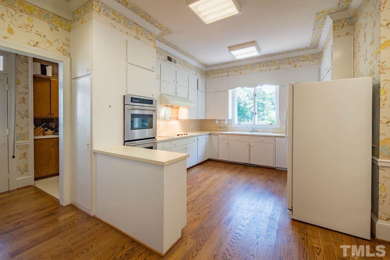 3210 Sussex Road Raleigh, NC 27612 - Photo 9 of 29 a kitchen with a refrigerator a stove top oven and wooden floor