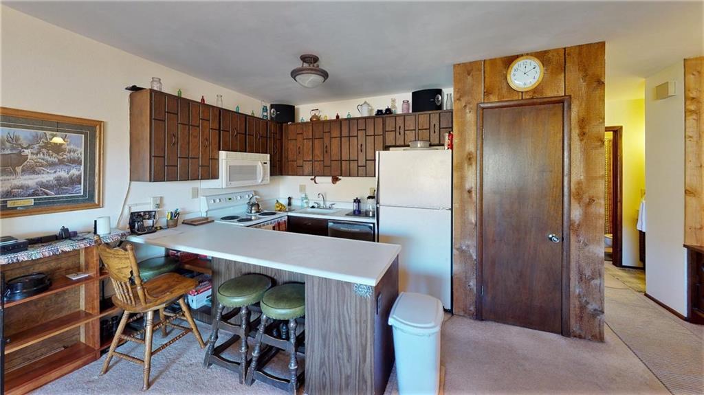 170 Evergreen Road, Unit 305 Dillon, CO 80435 - Photo 11 of 22 a kitchen with a refrigerator a stove and a dining table with wooden floor