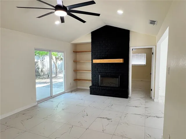 a living room with a fireplace and a ceiling fan