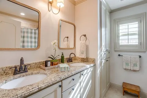 a bathroom with a granite countertop double vanity sink and mirror